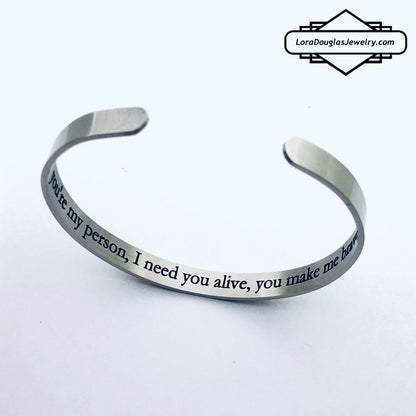 A stainless steel cuff bracelet with a secret message engraved on the inside, against the skin. The bracelet is blank on the outside.