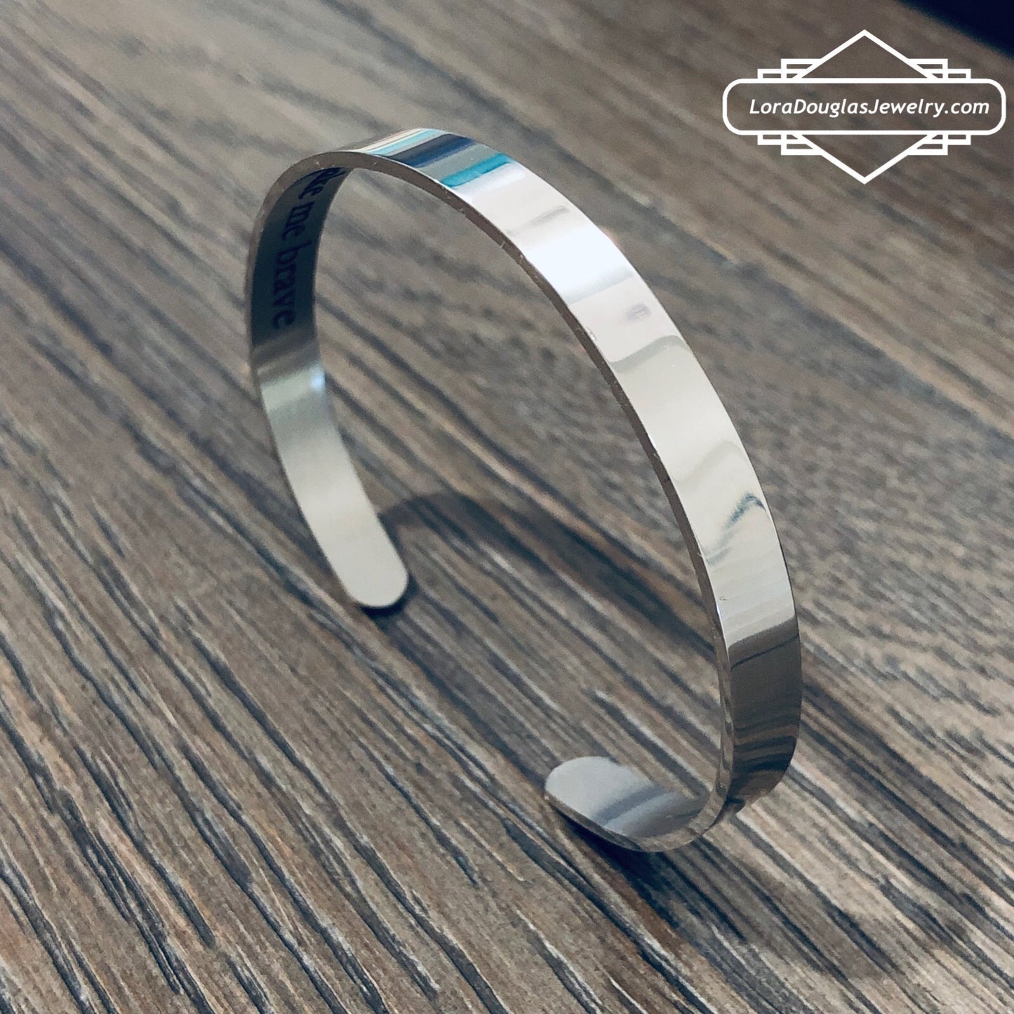 A stainless steel cuff bracelet with a secret message engraved on the inside, against the skin. The bracelet is blank on the outside.