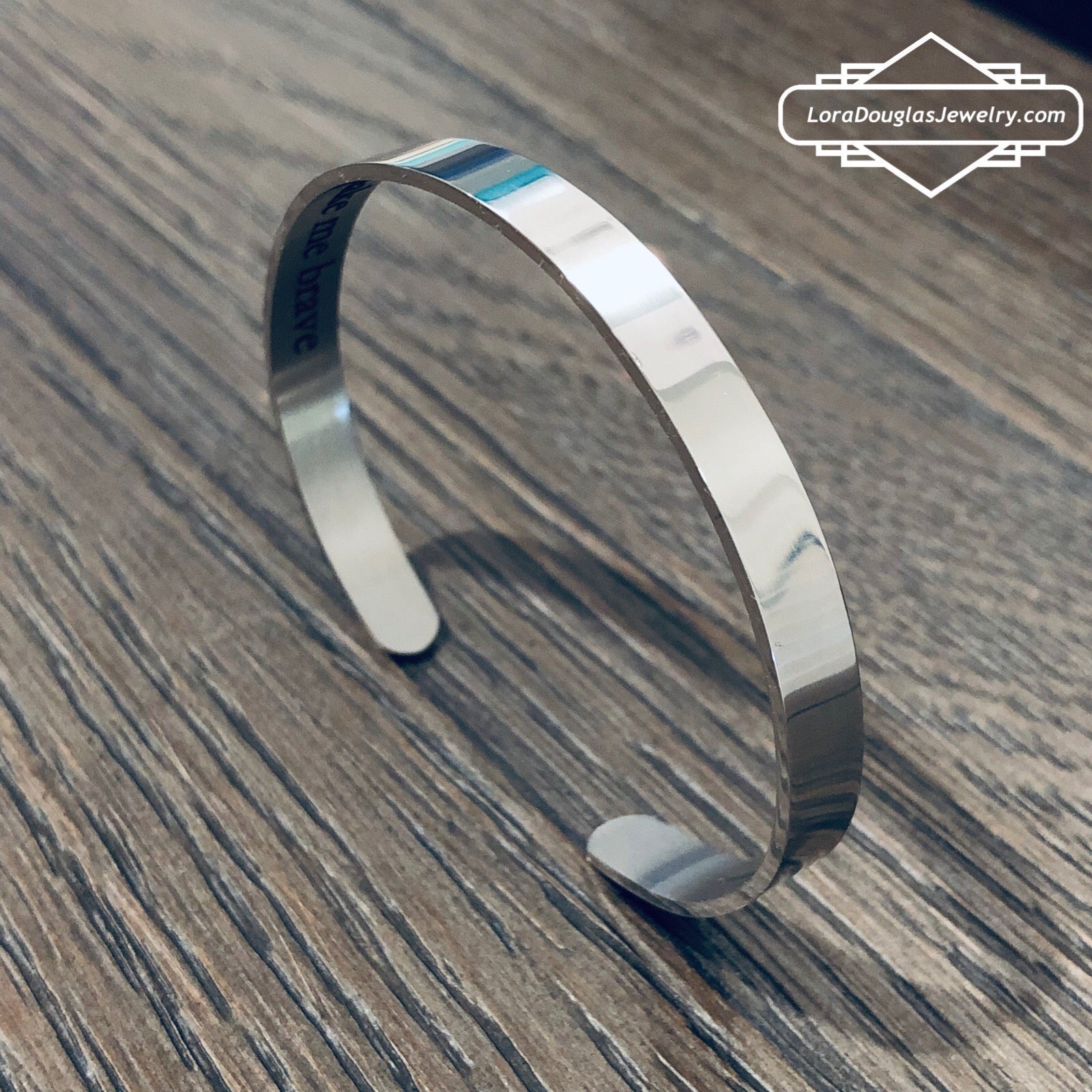 A stainless steel cuff bracelet with a secret message engraved on the inside, against the skin. The bracelet is blank on the outside.