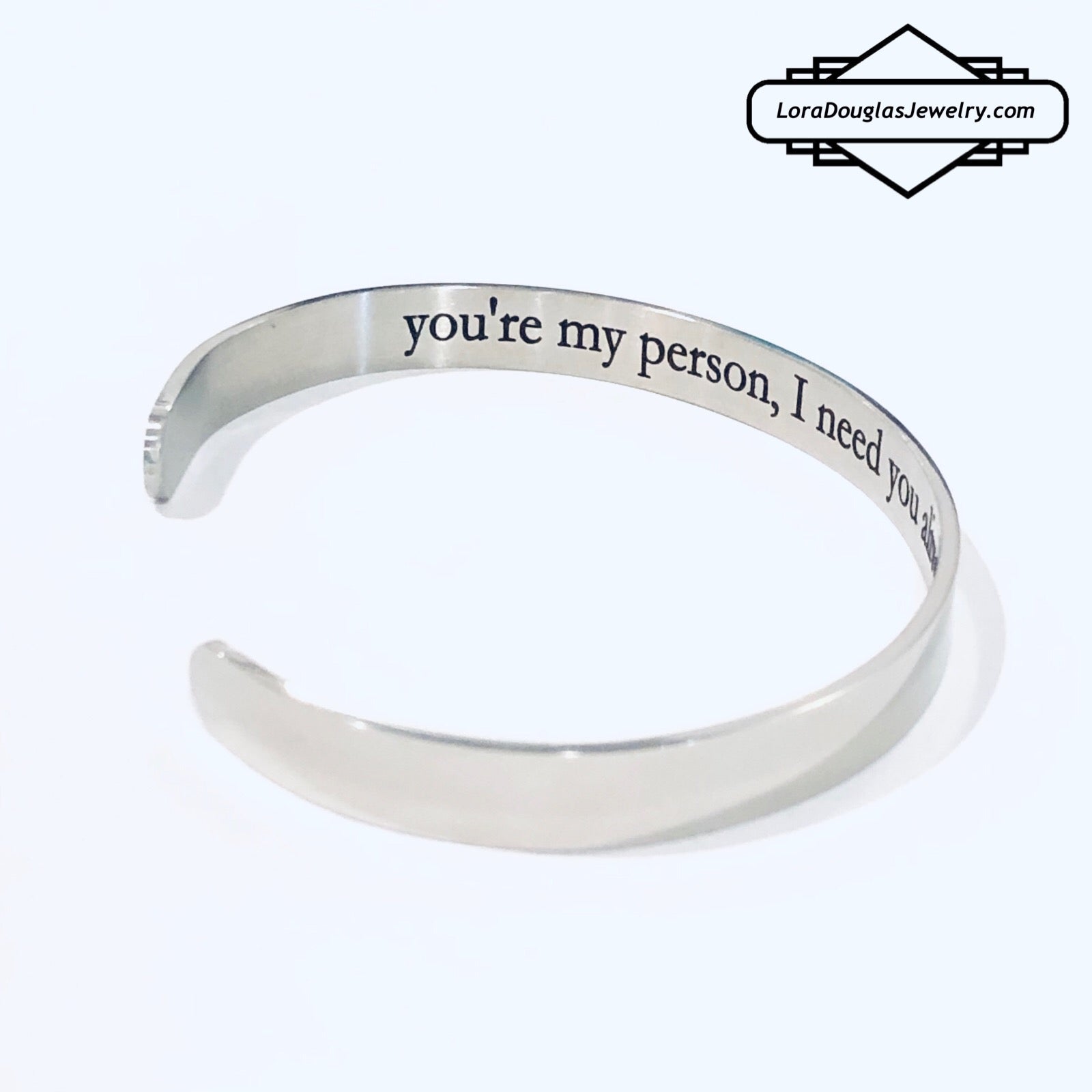 A stainless steel cuff bracelet with a secret message engraved on the inside, against the skin. The bracelet is blank on the outside.