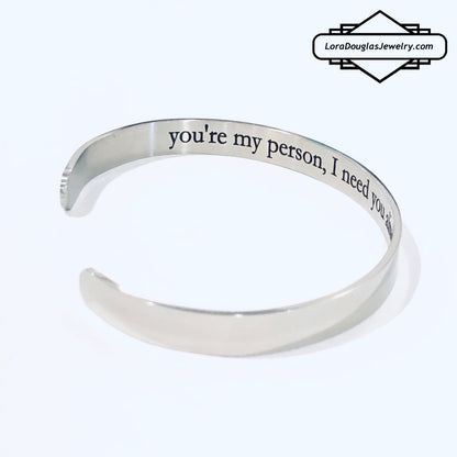 A stainless steel cuff bracelet with a secret message engraved on the inside, against the skin. The bracelet is blank on the outside.
