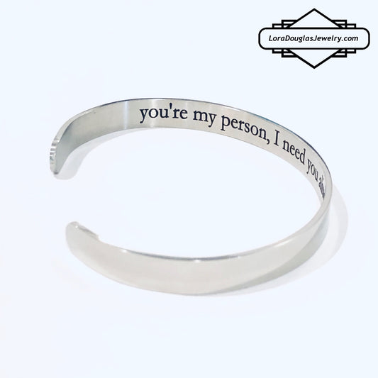 A stainless steel cuff bracelet with a secret message engraved on the inside, against the skin. The bracelet is blank on the outside.