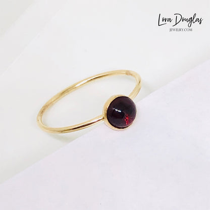 Gold-filled garnet solitaire ring, size 6, with a flat band and a polished finish, displayed on a plain background.