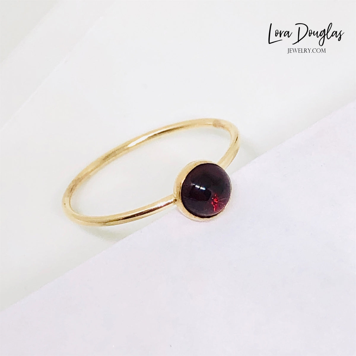 Red gemstone ring featuring a petite 5mm garnet set in warm gold filled metal, shown as a finished size 6 solitaire ring for shoppers searching for classic garnet jewelry and January birthstone gifts.
