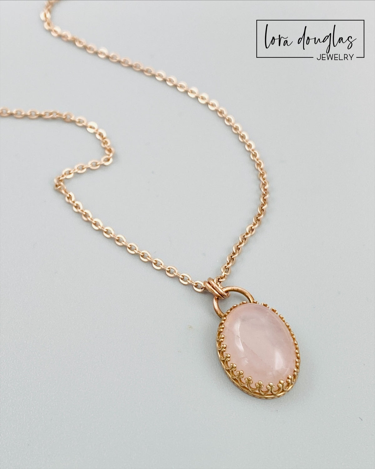 Rose quartz pendant necklace with a natural pink gemstone measuring 24mm x 14mm, set in bronze and paired with an 18 inch stainless steel chain finished with a lobster clasp.
