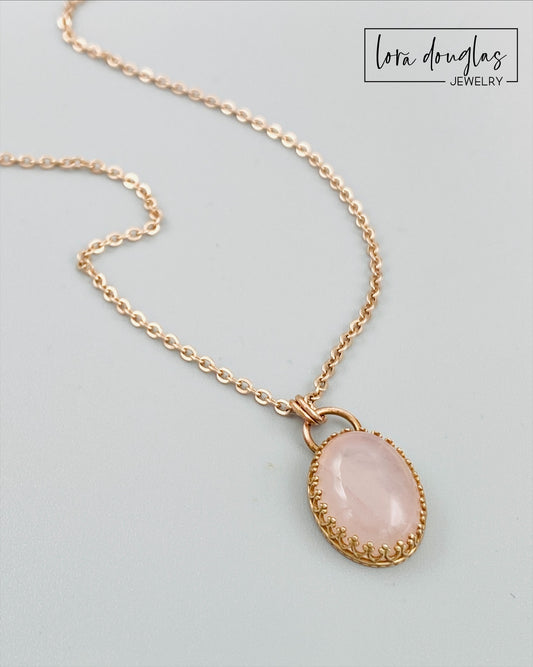 Rose quartz pendant necklace with a natural pink gemstone measuring 24mm x 14mm, set in bronze and paired with an 18 inch stainless steel chain finished with a lobster clasp.
