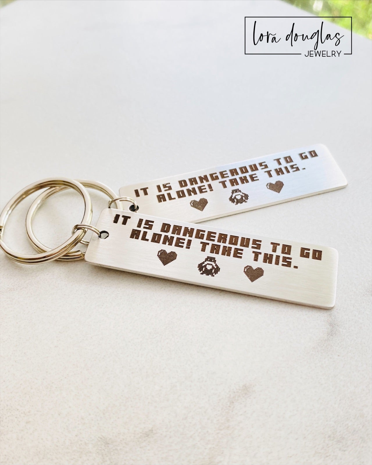 Stainless steel Legend of Zelda inspired keychain engraved with retro pixel art and the beloved "It is dangerous to go alone. Take this." message. Personalized back engraving available, making it a thoughtful anniversary gift for gamers and Nintendo fans.