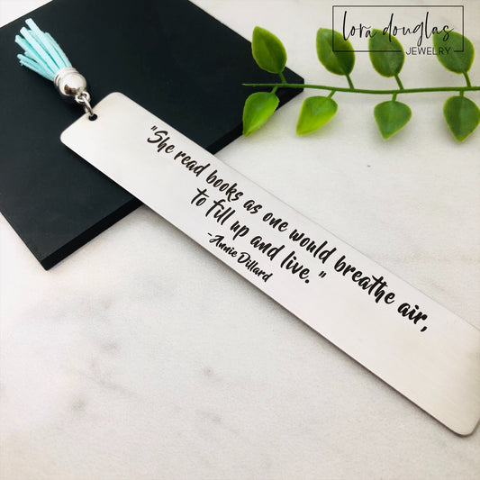 Stainless steel bookmark engraved with the literary quote "She read books as one would breathe air to fill up and live" and finished with a colorful faux suede tassel. Thoughtful gift for book lovers, librarians, teachers, authors, and avid readers.