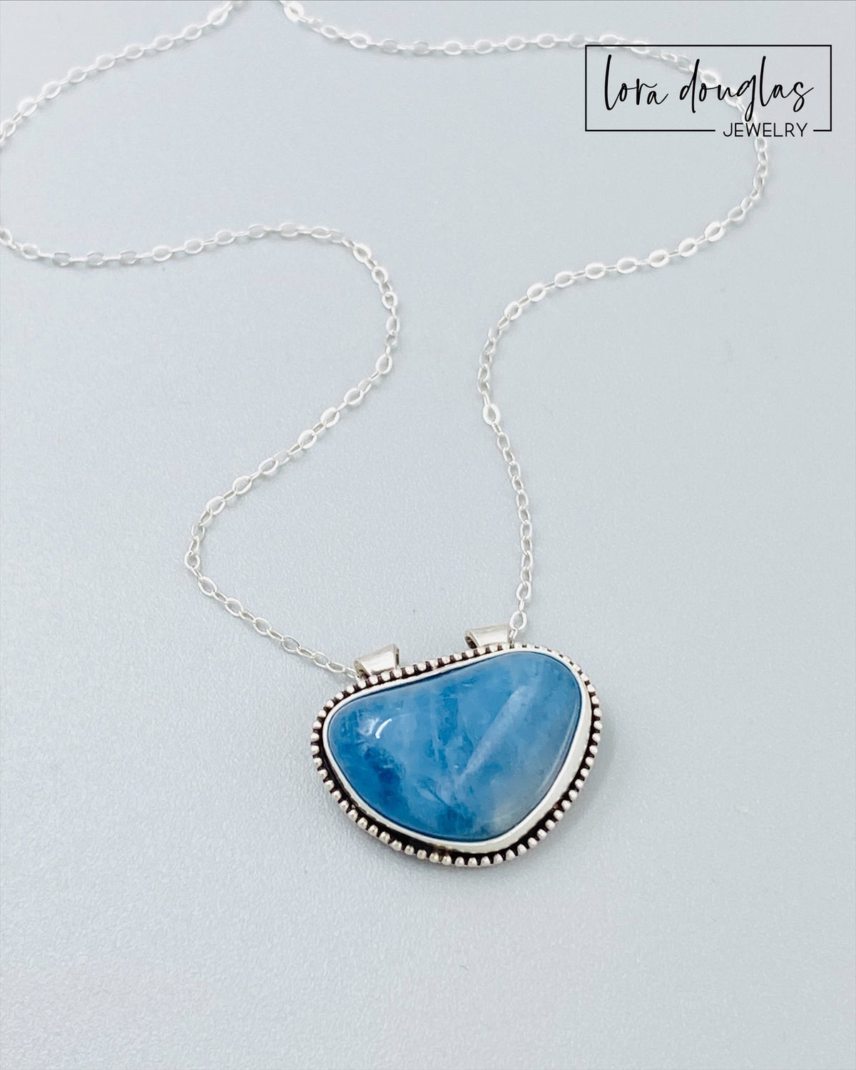 Sterling silver aquamarine pendant necklace featuring a natural blue gemstone in a substantial 20mm x 23mm setting, shown on an 18 inch antique patina chain for lovers of natural stone jewelry.

