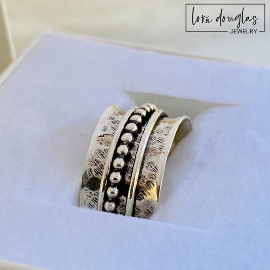 Sterling silver spinner ring featuring three movable components around a central band, shown in US size 8.5 with a 10.5mm width for shoppers looking for tactile fidget jewelry or an interactive silver ring.
