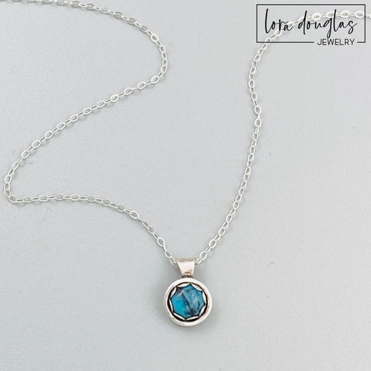 Natural turquoise necklace featuring a petite 5mm blue gemstone in an 11mm x 8mm sterling silver pendant, paired with an 18 inch sterling silver chain with an antique patina and C clasp.

