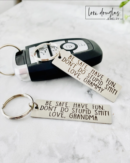 A personalized metal keychain with engraved text that reads 'BE SAFE HAVE FUN DON'T DO STUPID SHIT' accompanied by a space for custom text entry.