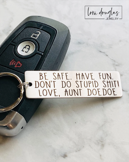 A personalized metal keychain with engraved text that reads 'BE SAFE HAVE FUN DON'T DO STUPID SHIT' accompanied by a space for custom text entry.