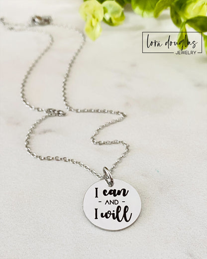 A silver-colored round pendant with the engraved text 'I CAN AND I WILL' on a chain, presented against a neutral background.
