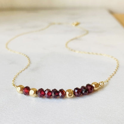 A garnet and gold-filled necklace with a meaningful inscription '1-4-3 I LOVE YOU' displayed on a card.