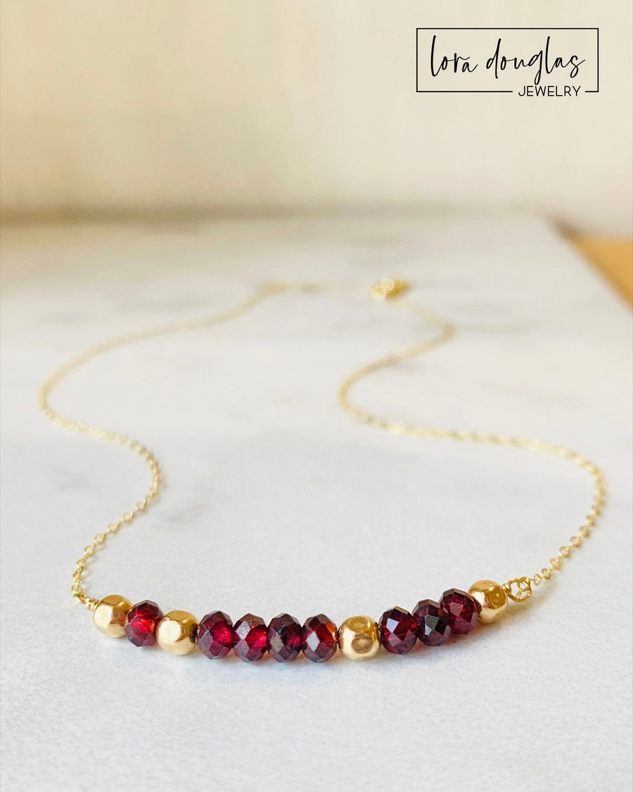 A garnet and gold-filled necklace with a meaningful inscription '1-4-3 I LOVE YOU' displayed on a card.