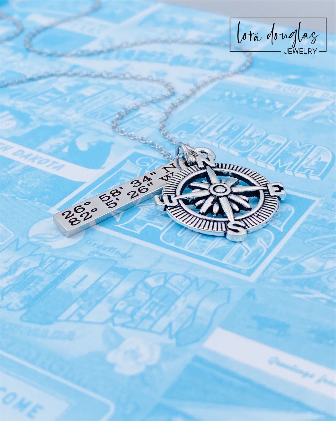 A silver compass necklace with a stainless steel pendant with personalized gps coordinates