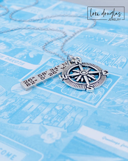 A silver compass necklace with a stainless steel pendant with personalized gps coordinates