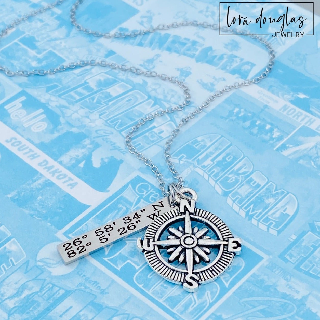 A silver compass necklace with a stainless steel pendant with personalized latitude and longitude coordinates