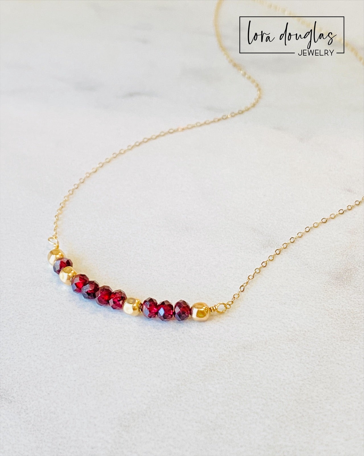 A garnet and gold-filled necklace with a meaningful inscription '1-4-3 I LOVE YOU' displayed on a card.