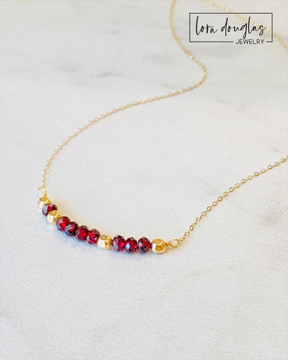 A garnet and gold-filled necklace with a meaningful inscription '1-4-3 I LOVE YOU' displayed on a card.