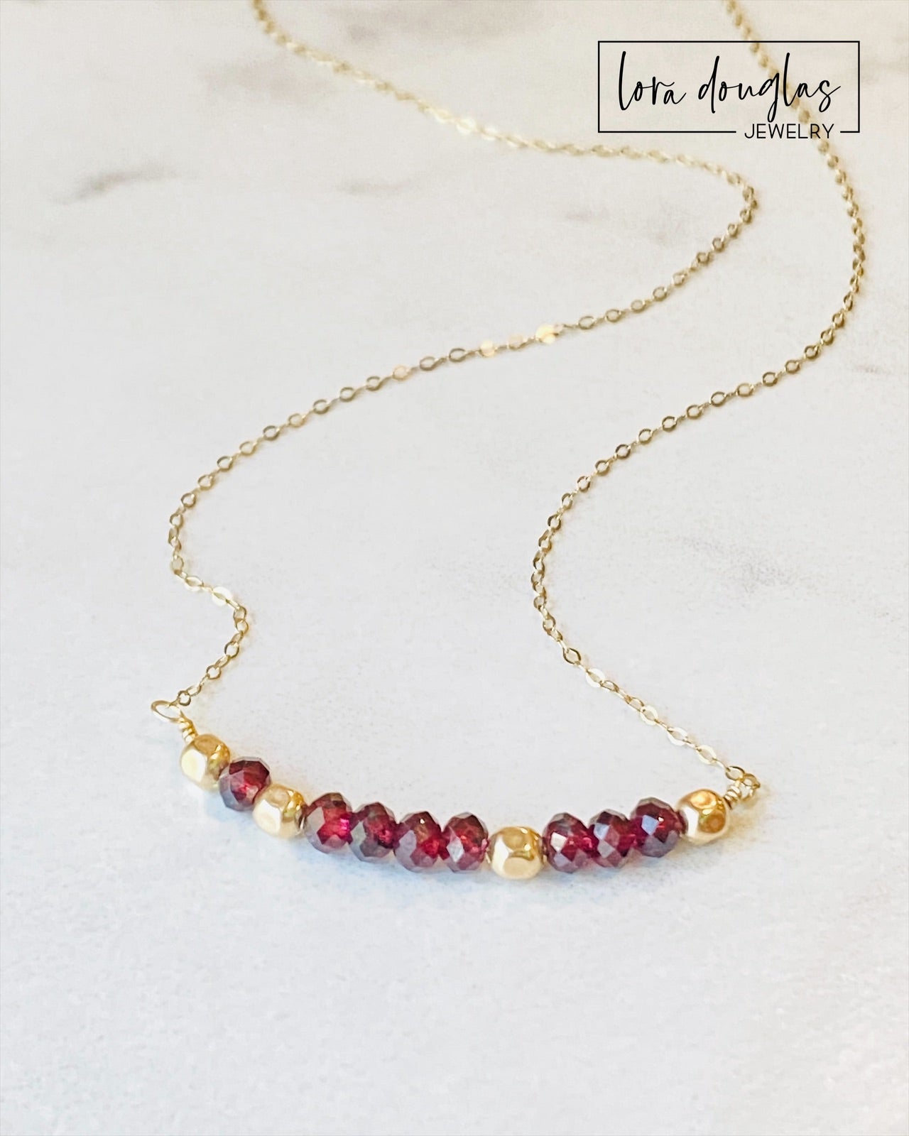 A garnet and gold-filled necklace with a meaningful inscription '1-4-3 I LOVE YOU' displayed on a card.