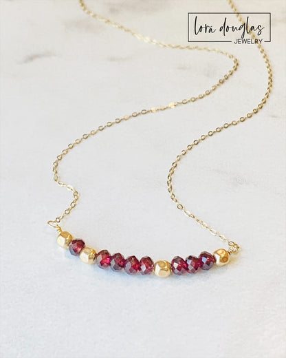 A garnet and gold-filled necklace with a meaningful inscription '1-4-3 I LOVE YOU' displayed on a card.