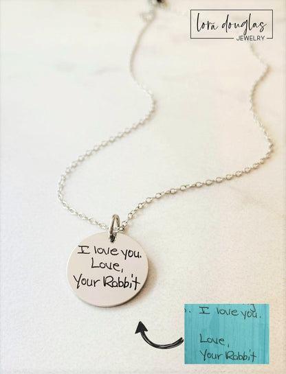 silver engraved necklaces displayed on a white background. Each necklace has a personalized handwritten message engraved on a disc charm, with varying text colors and styles.