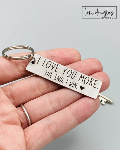 A stainless steel metal keychain with the engraved text 'I Love You More. The End. I Win.' 