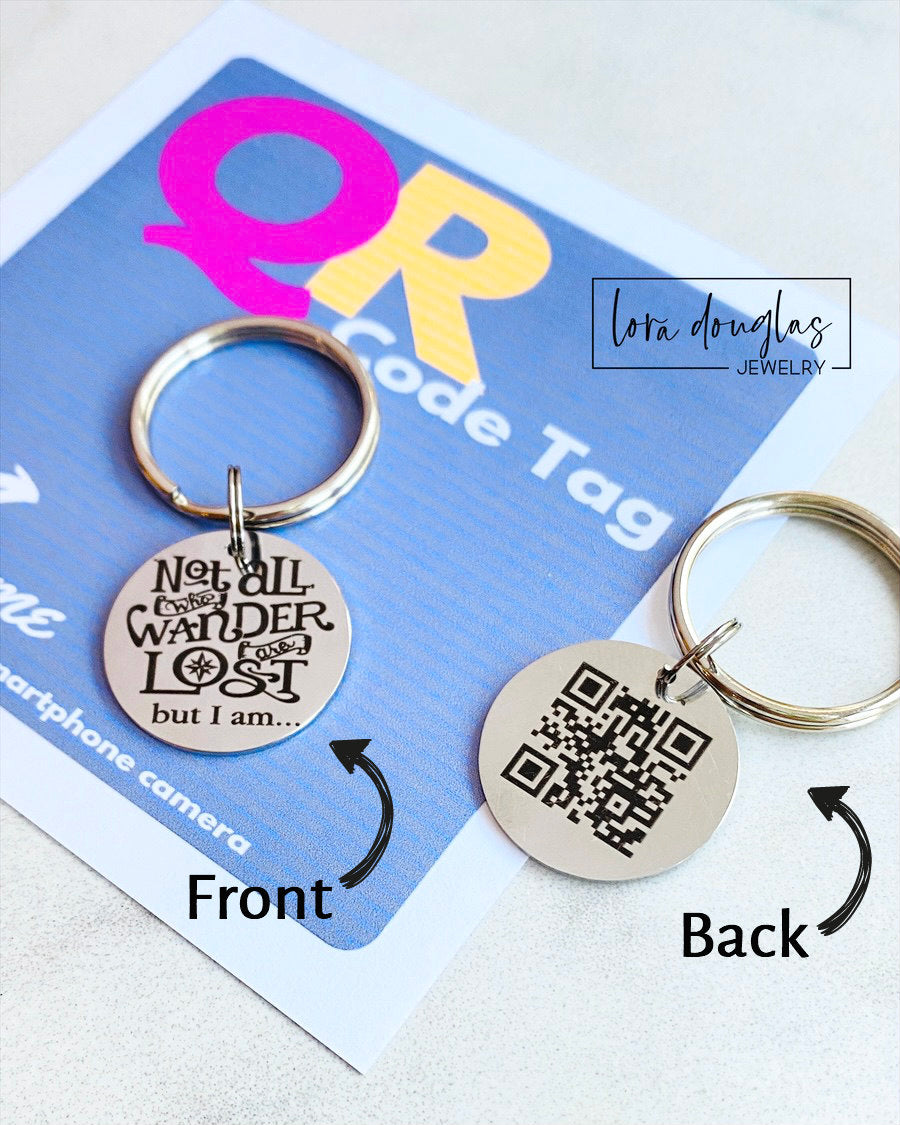 A stainless steel QR code pet tag in the shape of a keyring, with the engraved message 'Not all who wander are lost but I am.'.