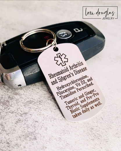 A stainless steel medical alert keychain displayed on a key. The tag has sample text for customization and indicates that additional text can be added on the back.