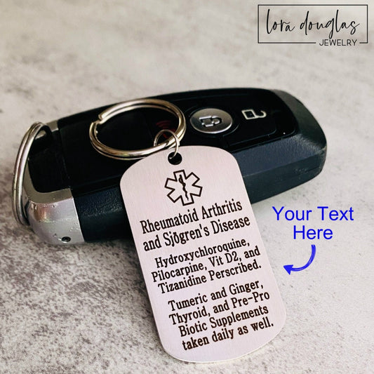 A stainless steel medical alert keychain displayed on a key. The tag has sample text for customization and indicates that additional text can be added on the back.