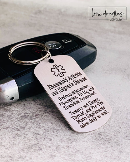 A stainless steel medical alert keychain displayed on a key. The tag has sample text for customization and indicates that additional text can be added on the back.