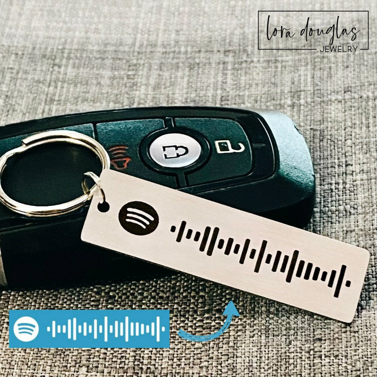 A stainless steel keychain with a laser engraved Spotify code, displayed next to a key fob.