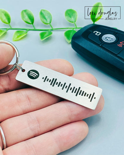 A stainless steel keychain with a laser engraved Spotify code, displayed next to a key fob.