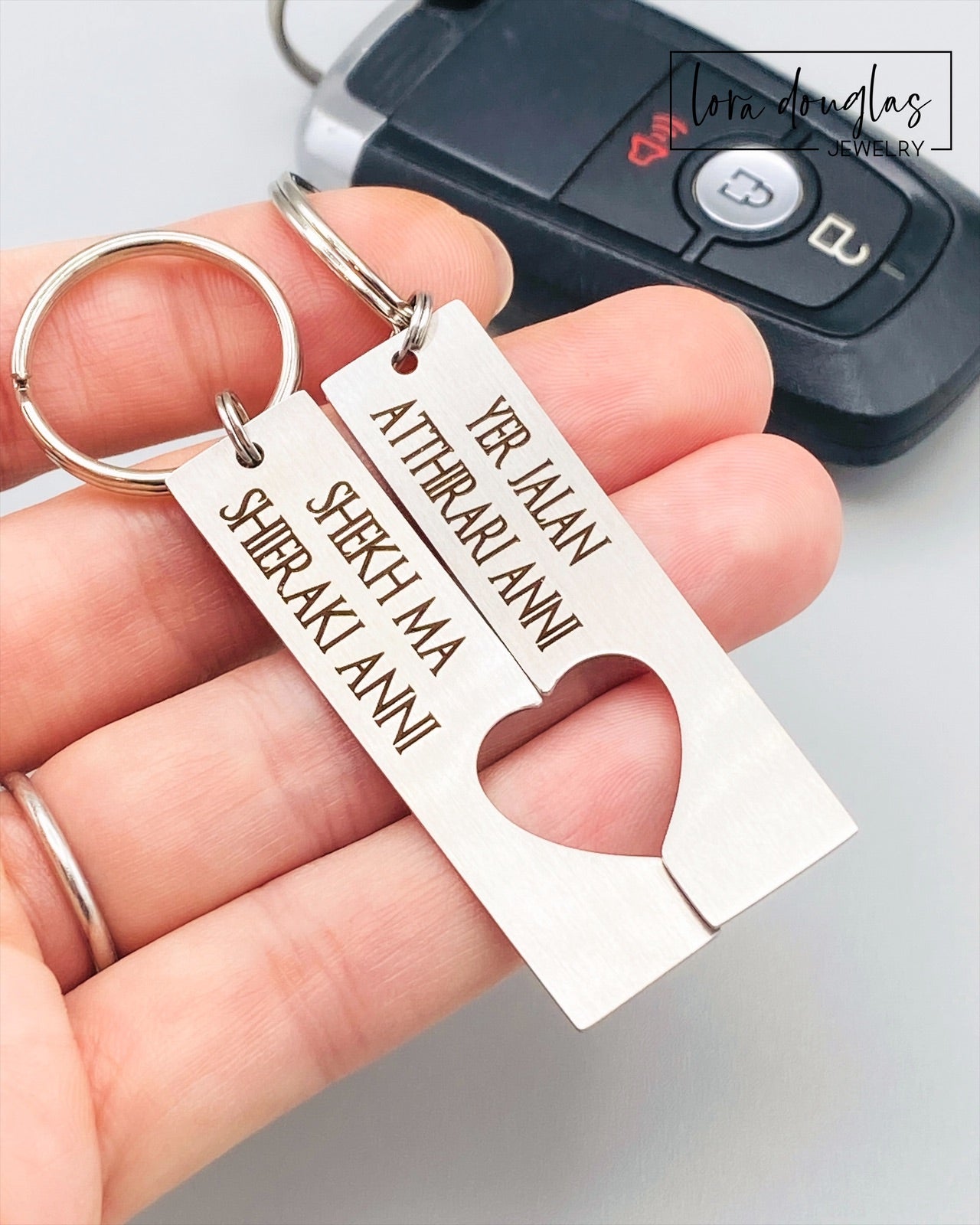 Two silver stainless steel keychains with Dothraki engraving, presented on a car key. One keychain reads 'Yer Jalan Atthirari Anni' and the other reads 'Shekh Ma Shieraki Anni', with optional personalization. Game of Thrones Gift