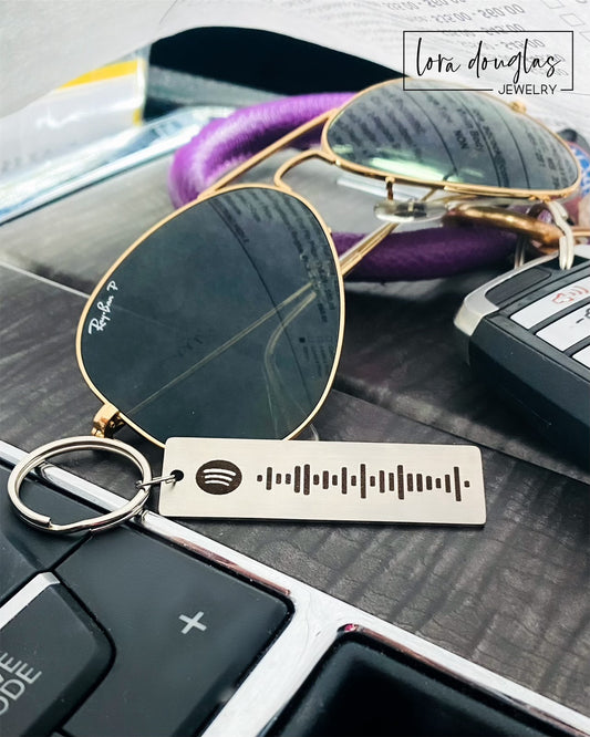 A stainless steel keychain with a laser engraved Spotify code, displayed next to a key fob.