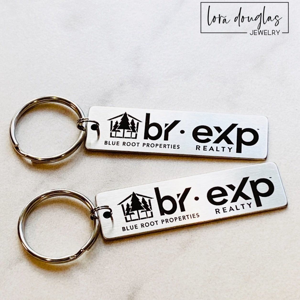 A silver stainless steel keychain with a custom logo engraving