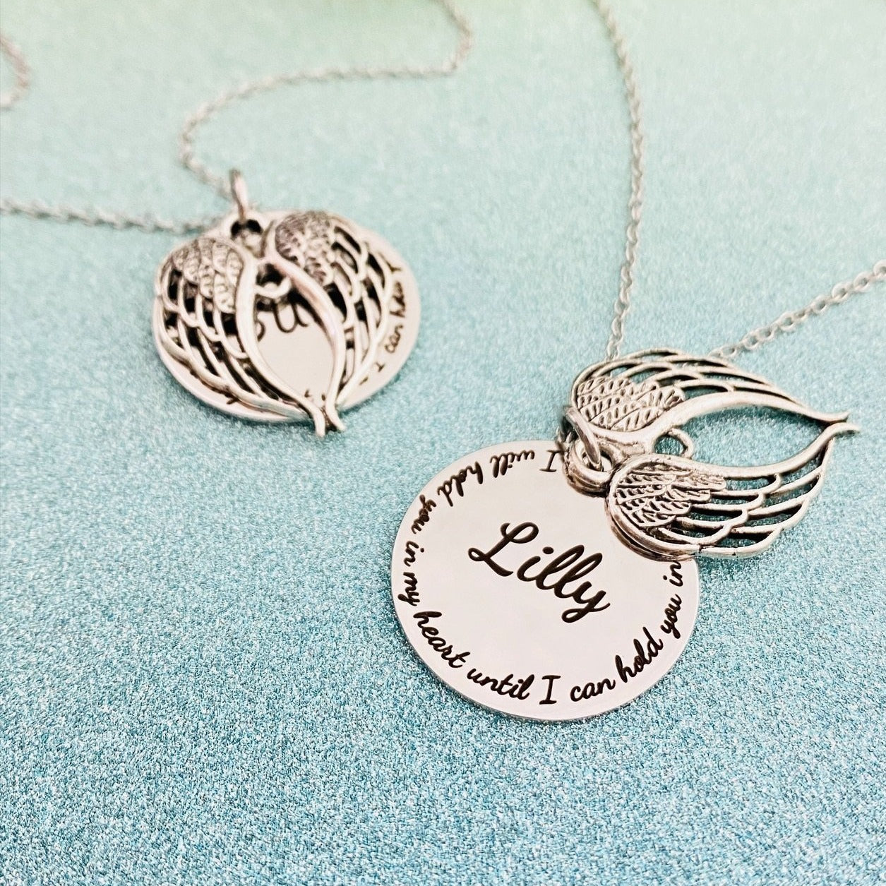 Two stainless steel memorial necklaces with swing lockets. One has a silver finish and the other has a gold tone. Angel wing charm necklace.