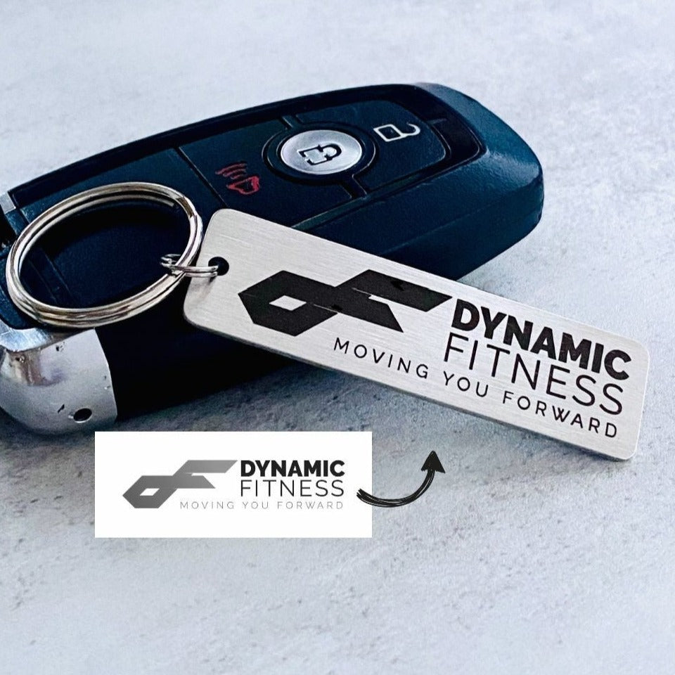 A silver stainless steel keychain with a custom logo engraving, displayed alongside a key fob.