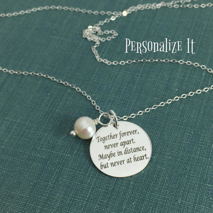 A stainless steel adjustable bangle bracelet with a round pendant that has engraved text 'Together Forever, Never Apart, Maybe in Distance, But Never at Heart'.