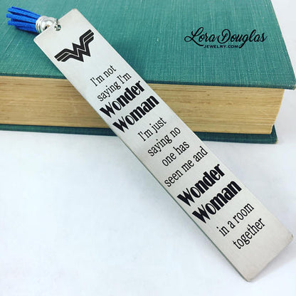 A stainless steel metal bookmark with an engraved Wonder Woman quote, placed on a book.