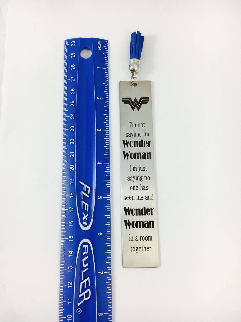 A stainless steel bookmarks with the phrases 'Teach Love Inspire' and 'Thank you for being my teacher' engraved on them, presented in a navy blue velvet pouch with tassels.