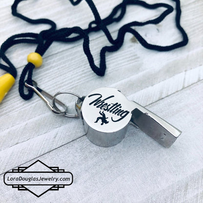 personalized stainless steel whistles with engraved text, one with 'COACH CARLOS' and sports icons, the other with 'FOOTBALL BASKETBALL SOCCER LIFEGUARD AND MORE'. Both whistles have a lanyard 