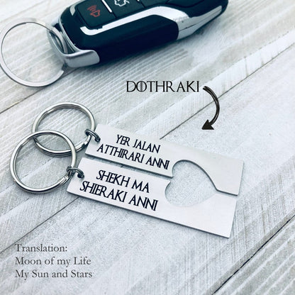 Two silver stainless steel keychains with Dothraki engraving, presented on a car key. One keychain reads 'Yer Jalan Atthirari Anni' and the other reads 'Shekh Ma Shieraki Anni', with optional personalization. Game of Thrones Gift