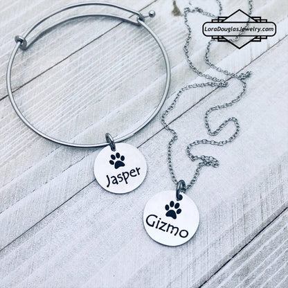 A stainless steel paw print necklace and bangle, with your pet's name engraved on them.