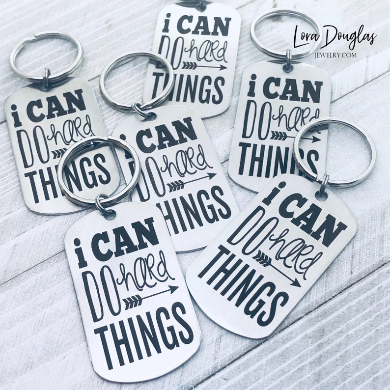 stainless steel keychains with the engraved text 'I CAN DO HARD THINGS' on a black background.
