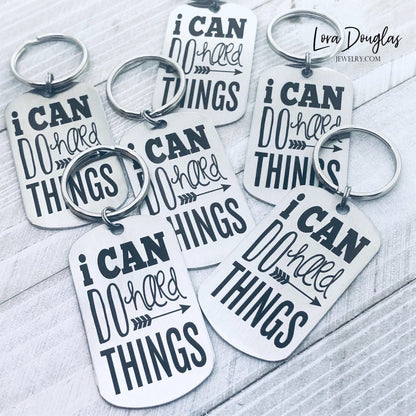 stainless steel keychains with the engraved text 'I CAN DO HARD THINGS' on a black background.