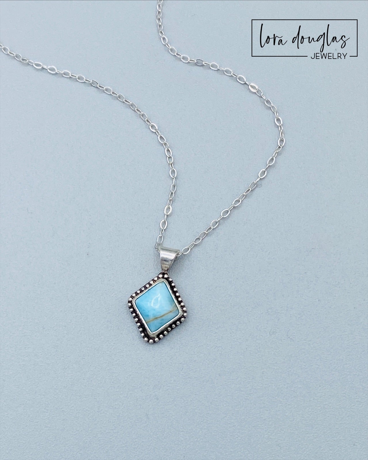A sterling silver pendant necklace with a turquoise stone and a silver chain.