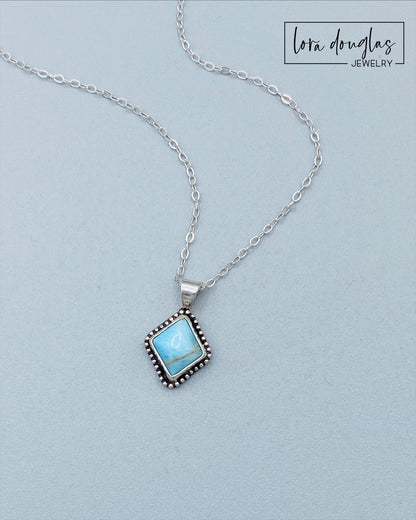 A sterling silver pendant necklace with a turquoise stone and a silver chain.
